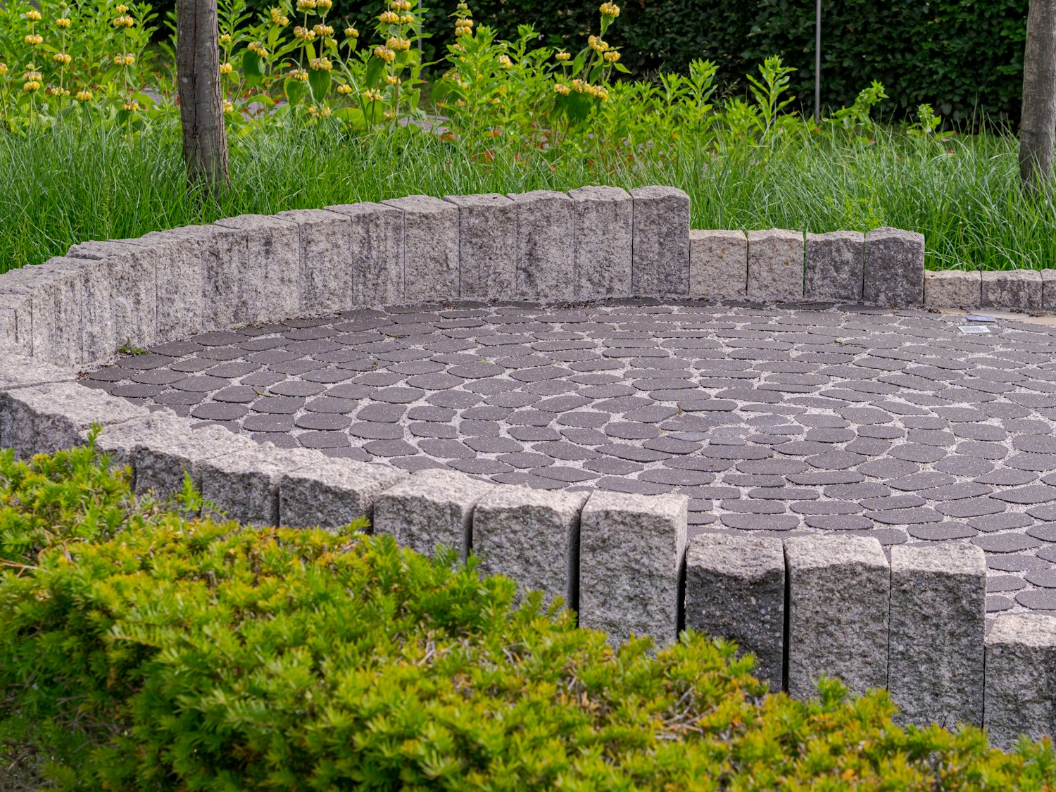 Circular block paving patio with granite sett border and planting